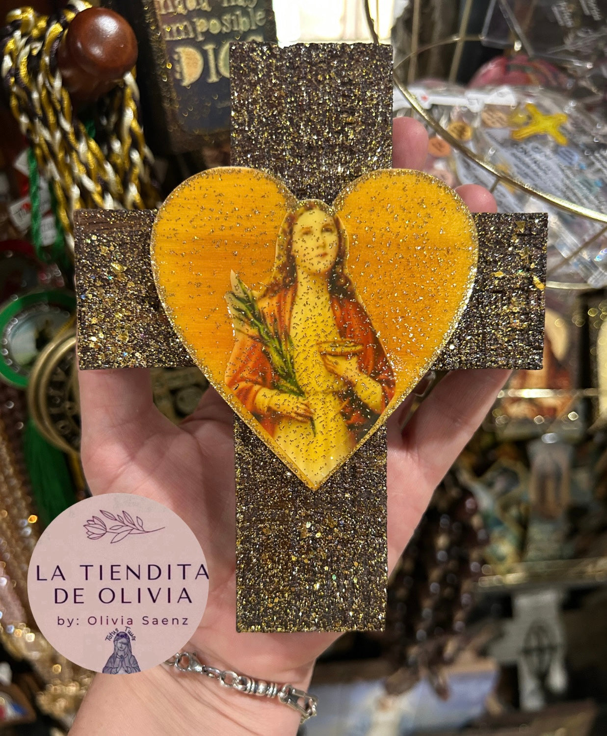 SANTA LUCÍA.                                   Mini Cruz de Madera para colgar 
Medidas aproximadas 4.5" X 6"
Elaborada y diseñada por La Tiendita de Olivia